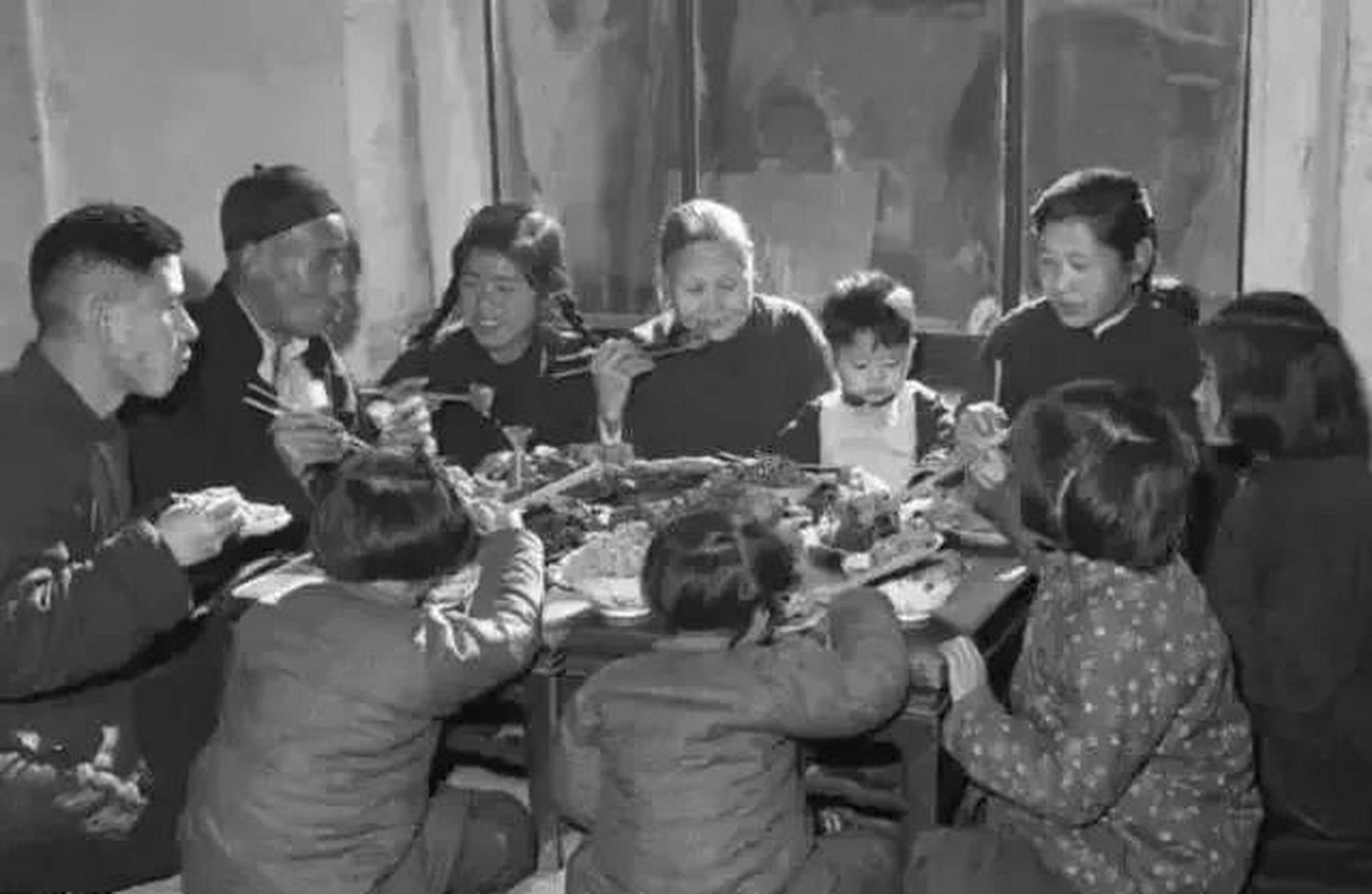 七十年代全家人围在一桌吃年夜饭的场景; 照片中爷爷和父亲坐在一起
