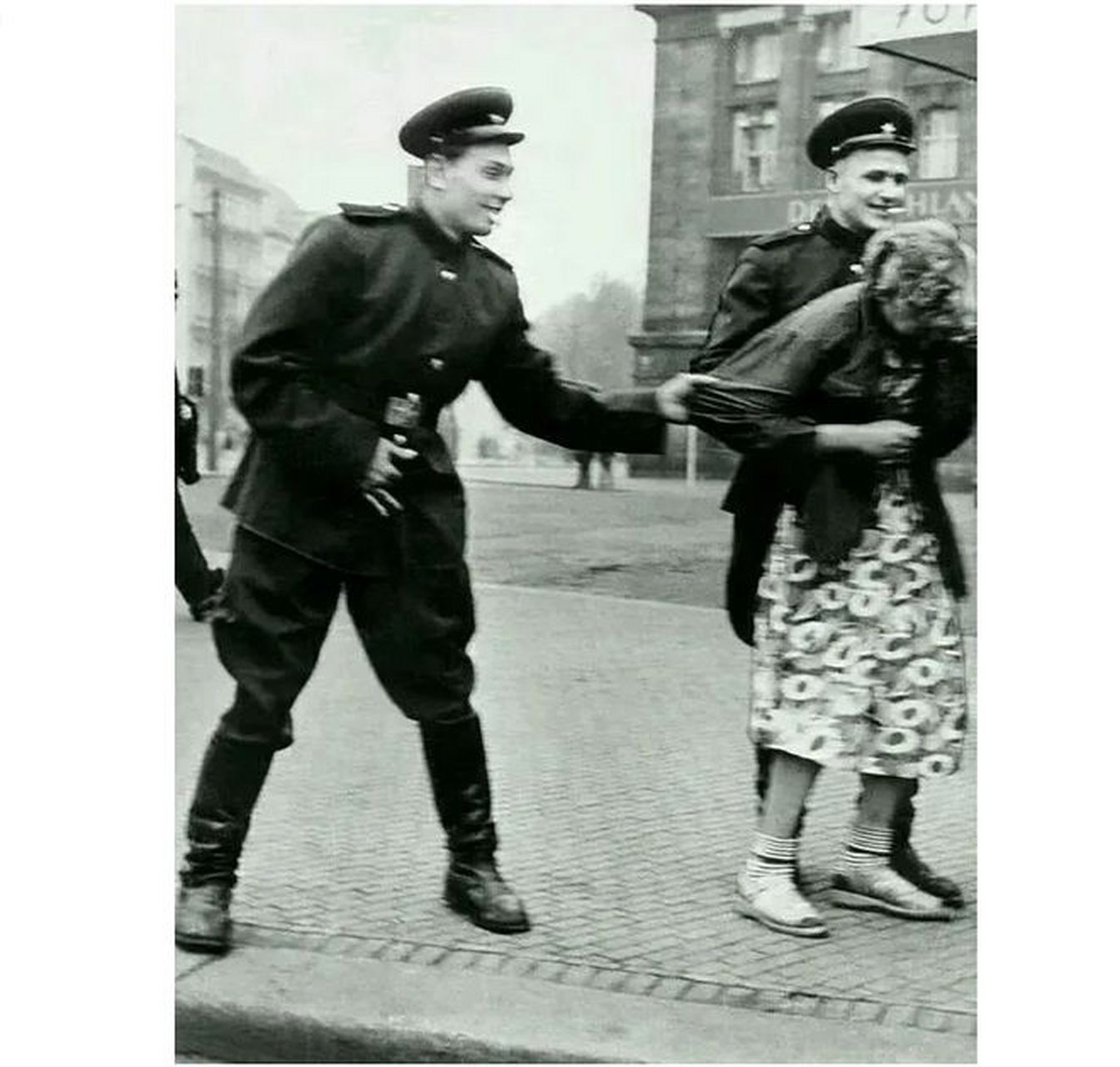 这张照片拍摄于1945年的德国柏林,两个苏联士兵手牵着一个德国妇女的