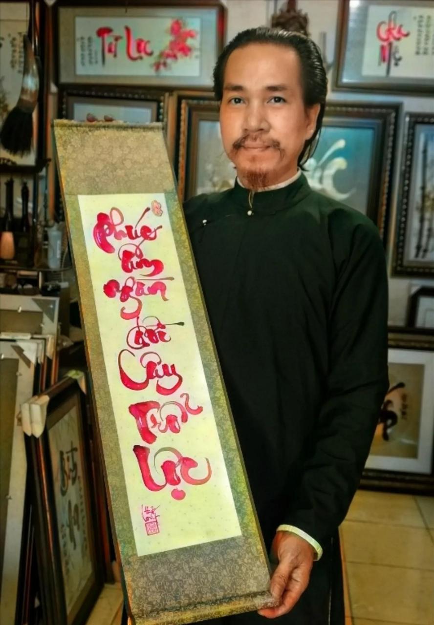 这是一位来自越南的书法家,只见他留着明朝发型,手里正在展示他的"