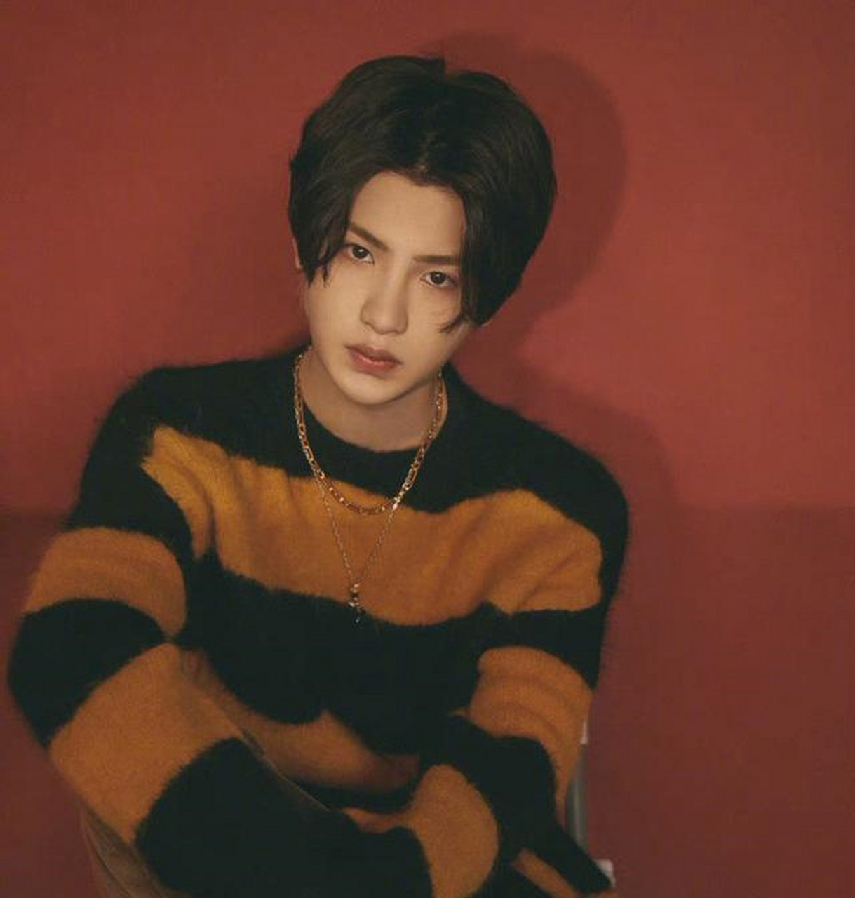 黄明昊身穿橙黑条纹针织衫,中分黑发尽显温柔潮男气质