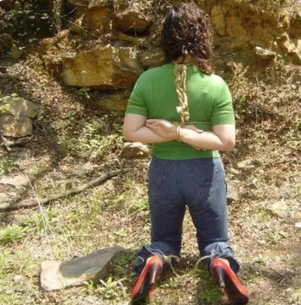 90年代,一名女犯人被绑在绳子上跪在地上行刑,照片中的她非常新潮时尚