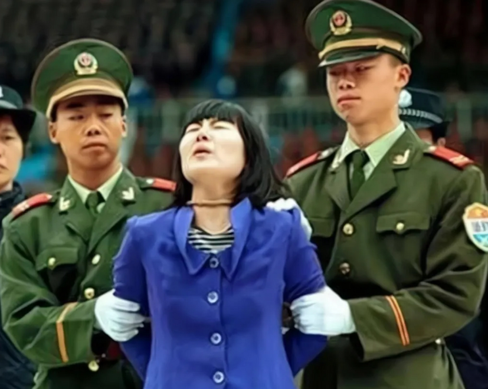 90年代,公审大会上,一名被绑着"锁喉绳"的女子,镜头中的女子头被迫向