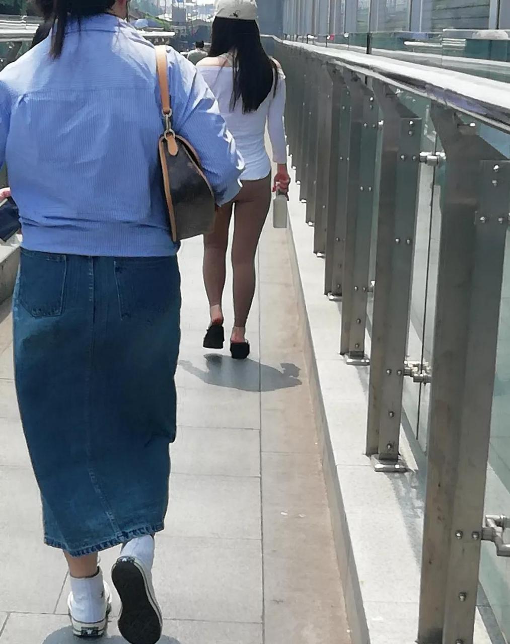 一位女士穿着很薄的紧身裤从旁边走过,都勒出了一条缝,回头率杆杠的