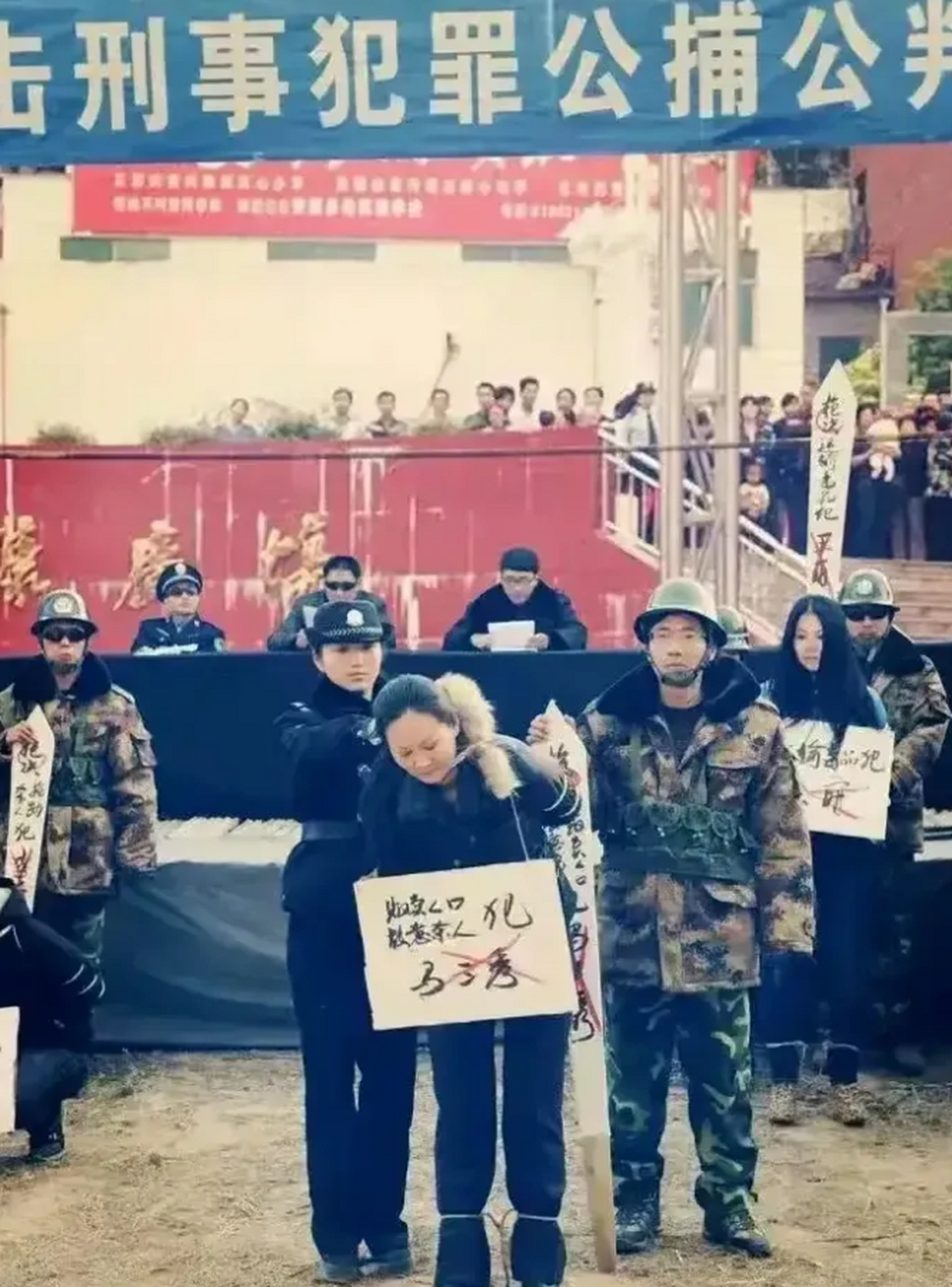 2001年某地一场公捕公判大会,两名年轻的女犯被押解到现场聆听法院的