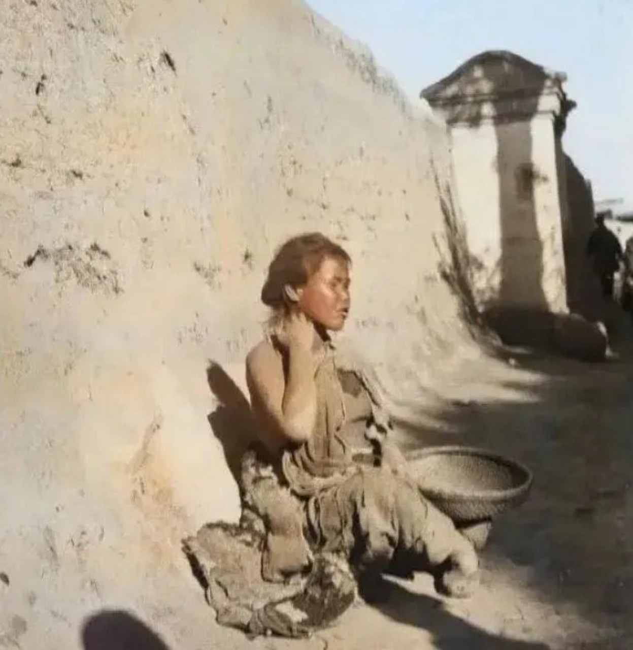 1919年,甘肃兰州,美国摄影师拍的女乞丐,她坐在城墙下等路过的人施舍