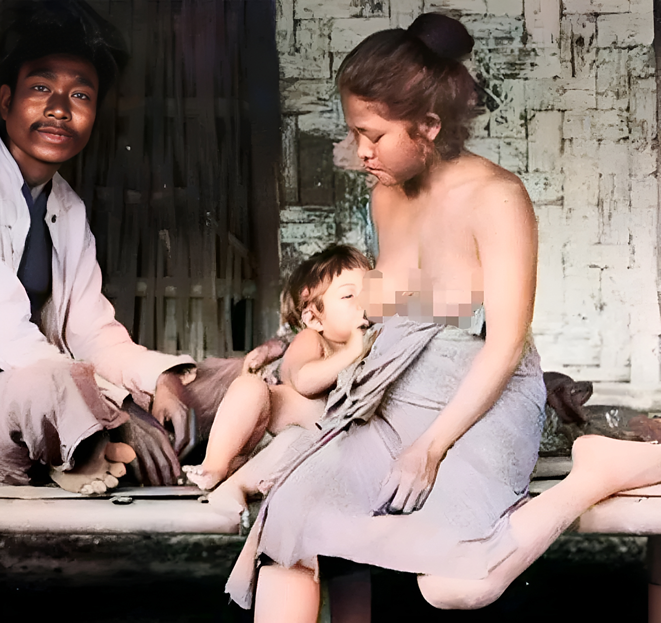 在60年代的印尼某个村庄,一位年轻的母亲坐在门前的木板上哺乳她的