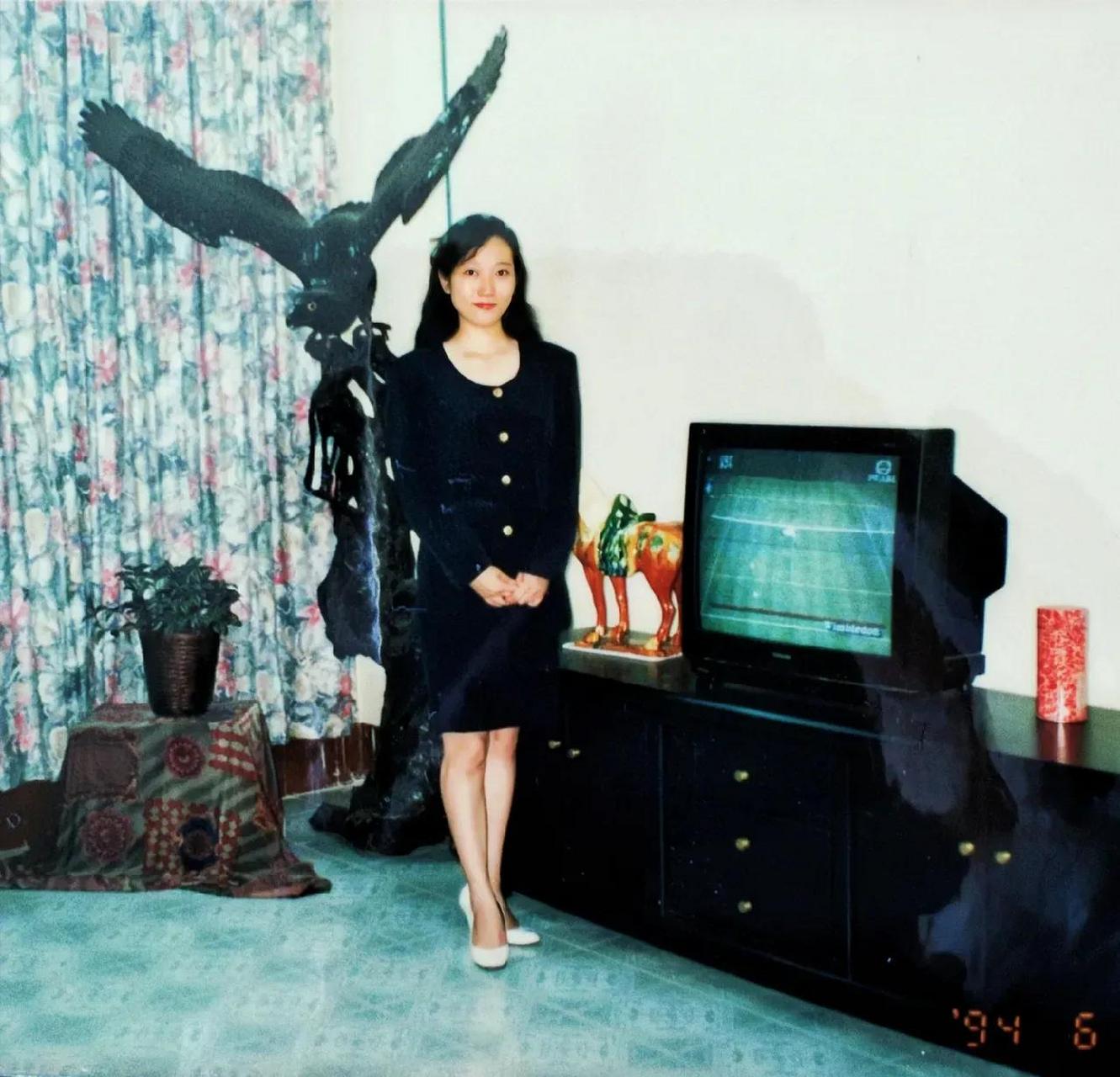 90年代,一个穿着一身黑色连衣裙的漂亮姑娘在家中客厅里的留影.