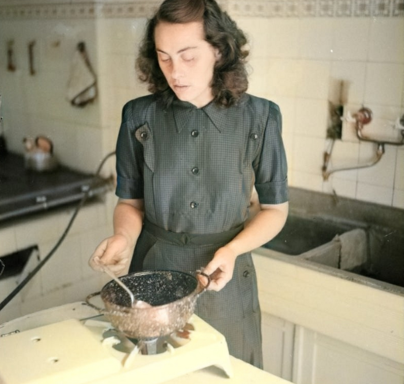 1950年代,德国,家庭主妇拿德军的钢盔烧汤做饭.