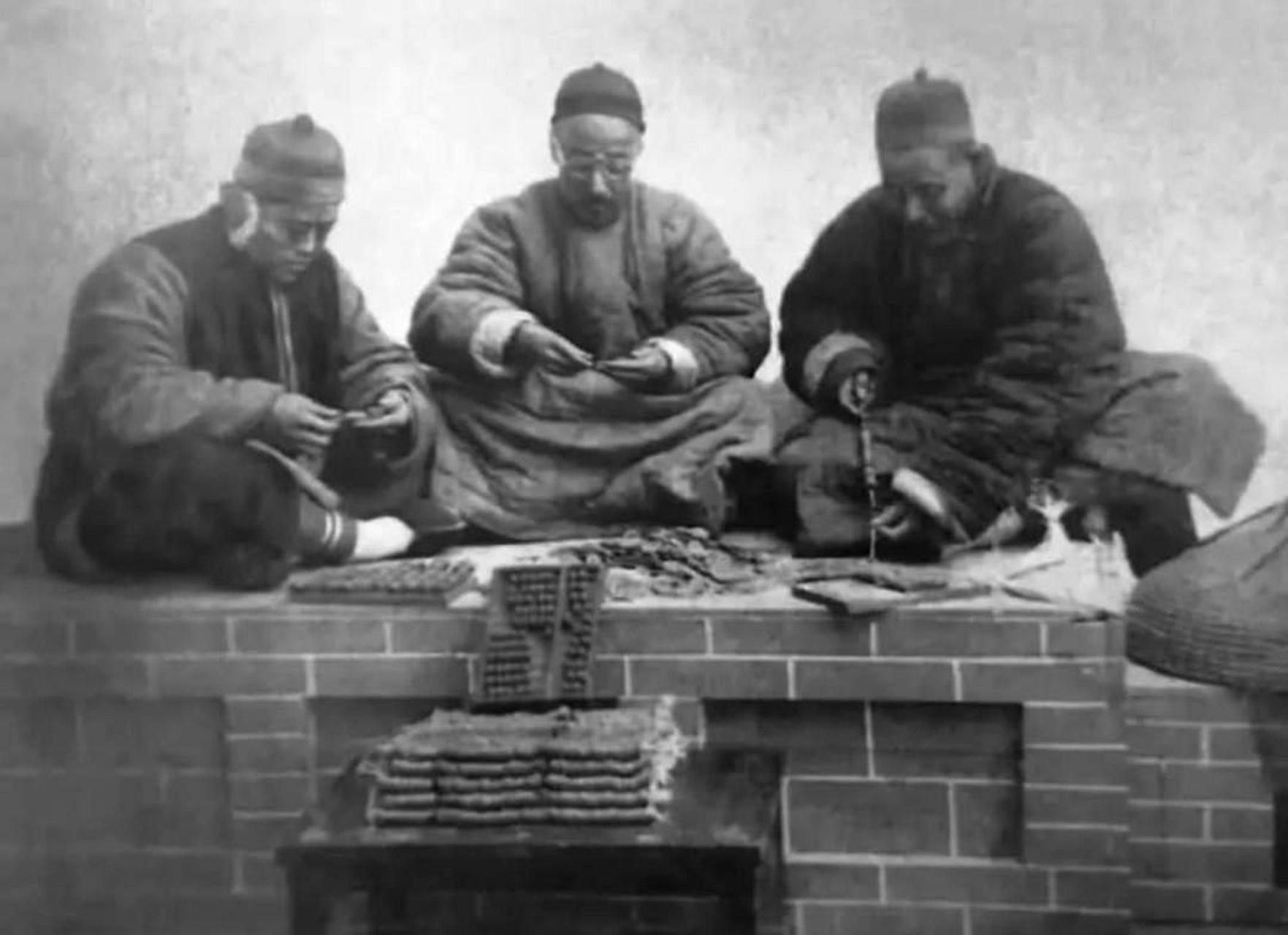 这张照片真实地展现了三位地主老财坐在炕上数钱的场景,他们手中的一
