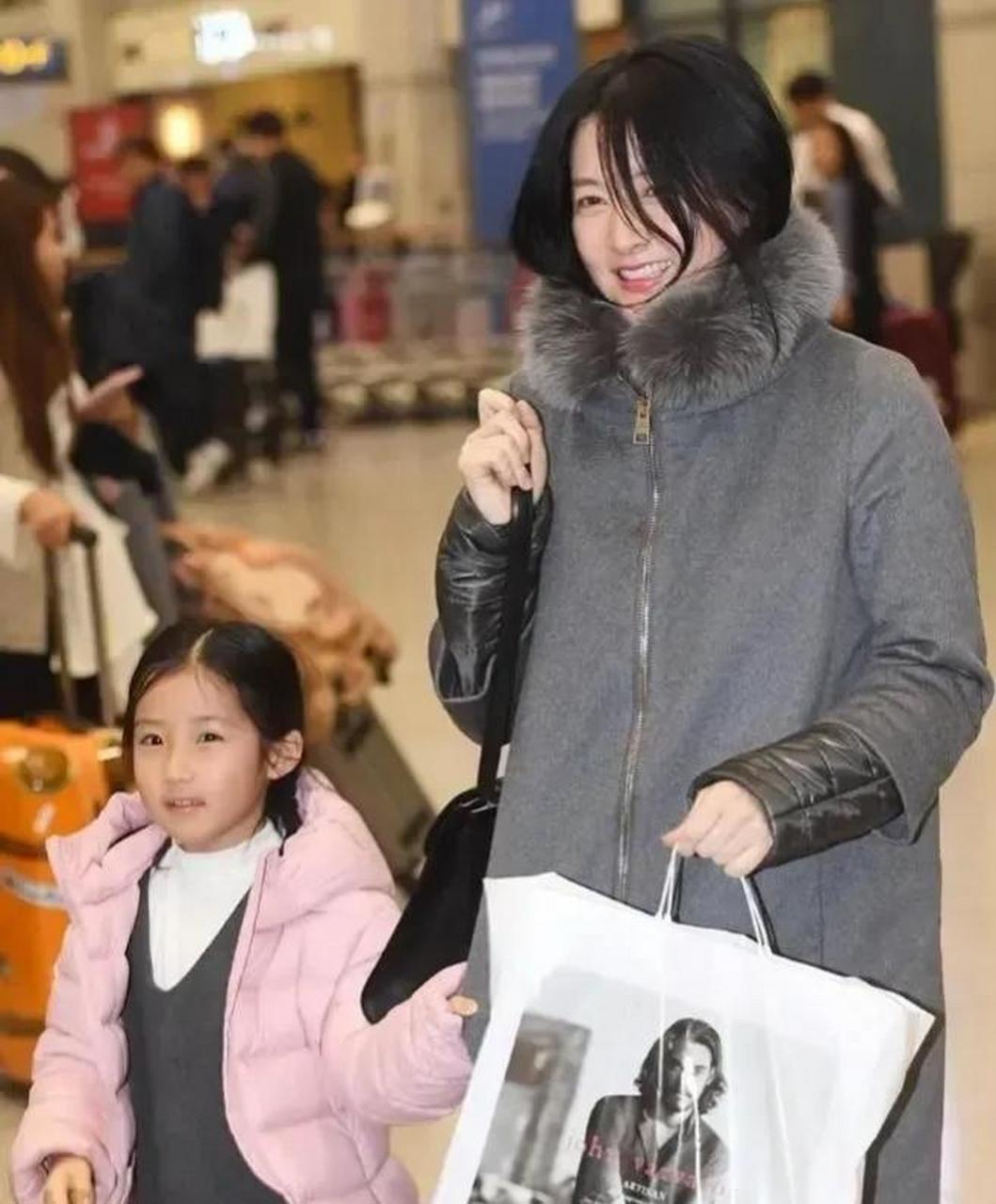 51岁李英爱携一对双胞胎儿女素颜走机场,一袭灰色毛领外套出镜,简约
