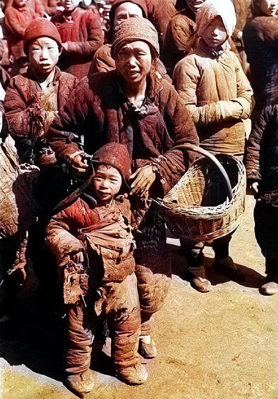 1946年,湖南地区,一个三四岁的小孩穿着破旧的衣服,双手端着一个碗,坐