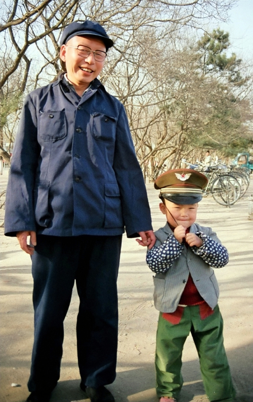 八十年代,在北京,一位老人带着孙子出来玩耍.