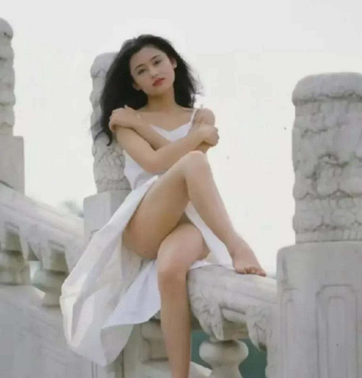 17岁不到的陈红, 身着白色吊带连衣裙, 环抱手臂, 露出白皙修长的双腿