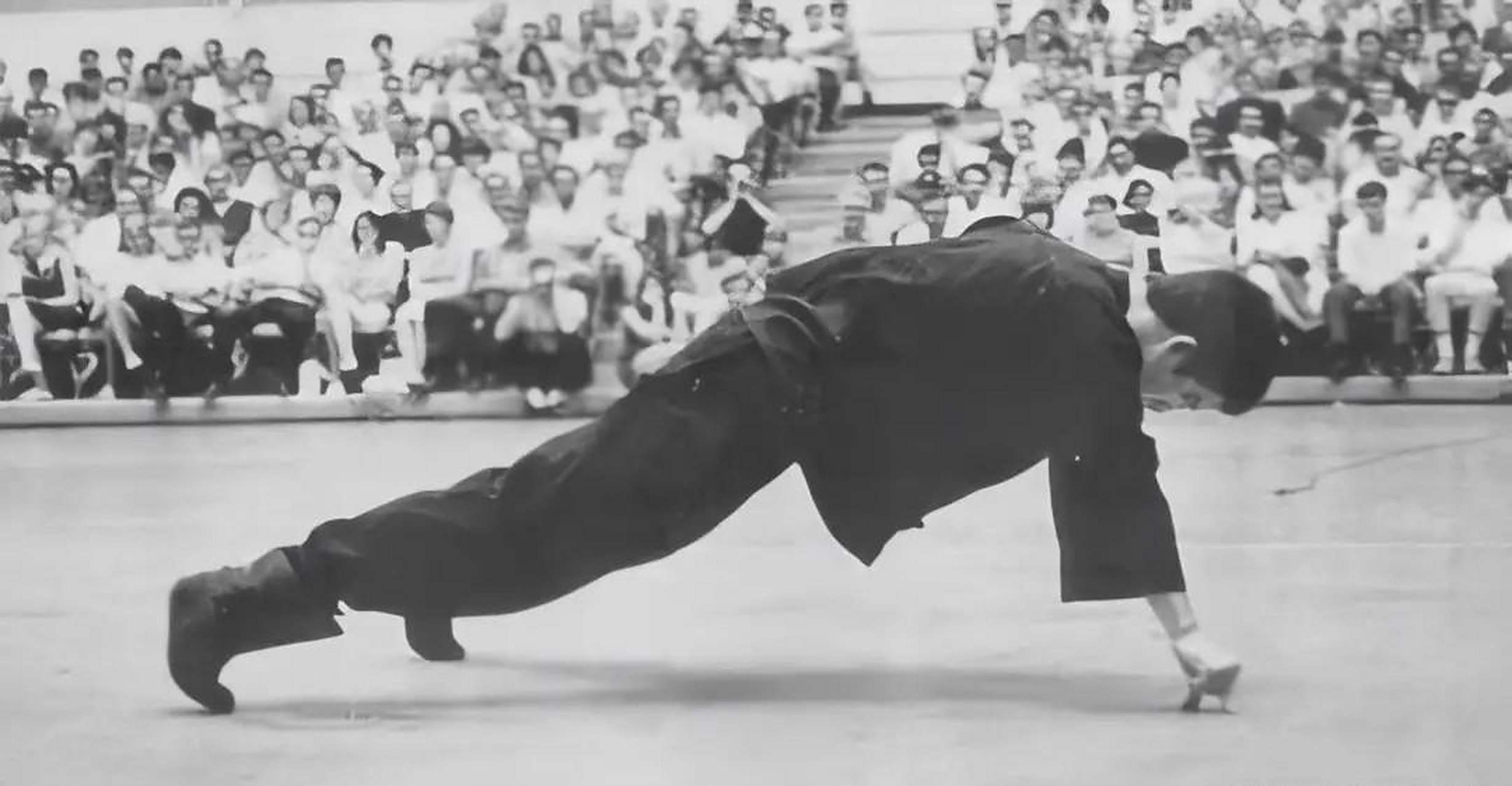 照片拍摄于1965年,当时李小龙正在向台下观众展示单手二指禅俯卧撑