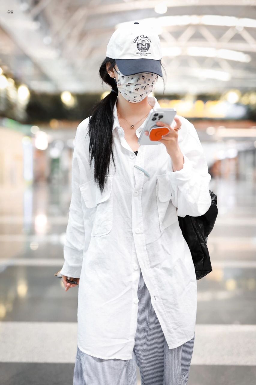 章若楠现身机场 身穿白色宽松中长款衬衫, 搭配蓝色条纹休闲裤 小脏鞋