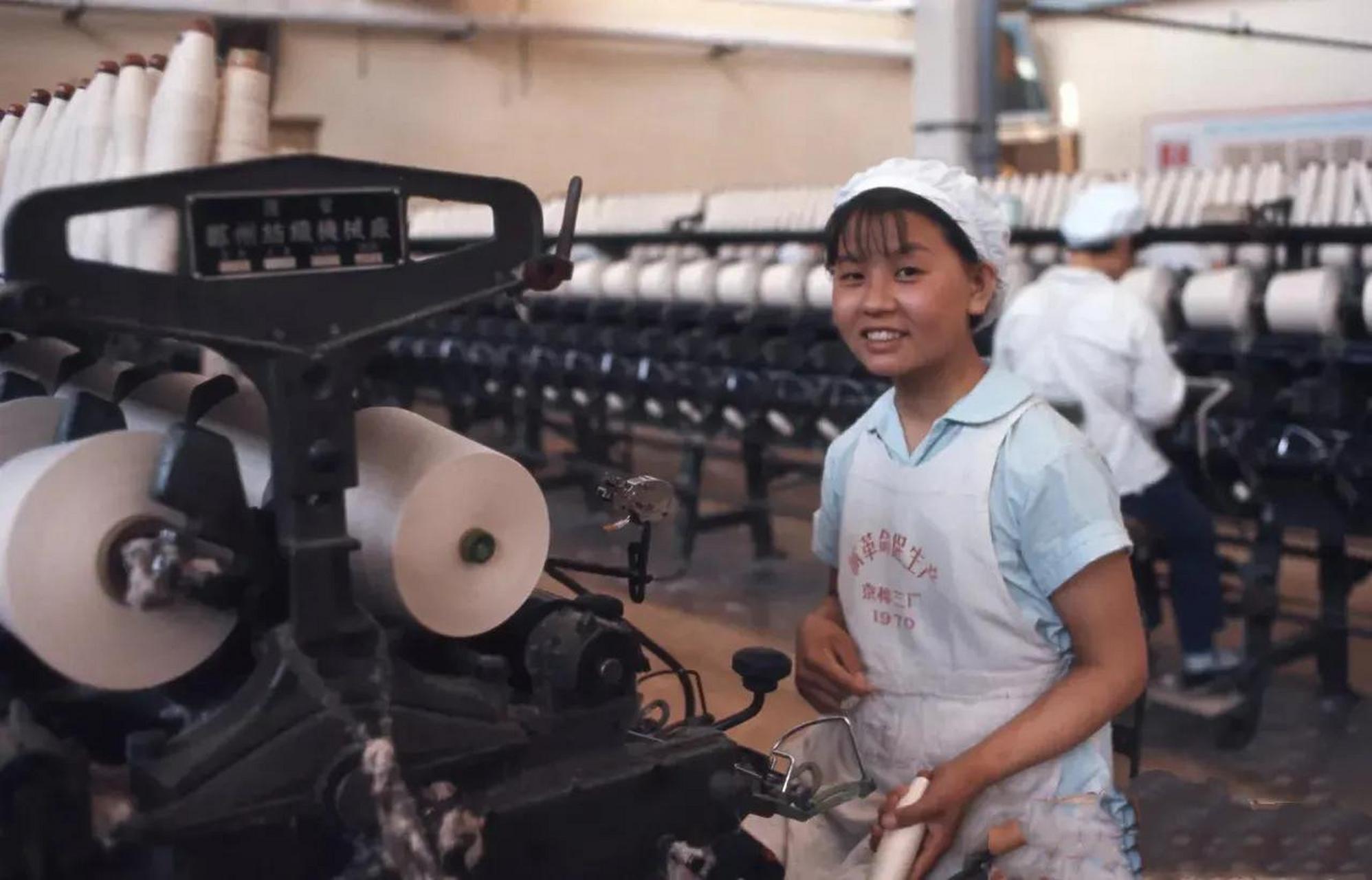 在1971年的北京,京棉三厂纺织车间里,一名年轻的女工正专注地在纺织机
