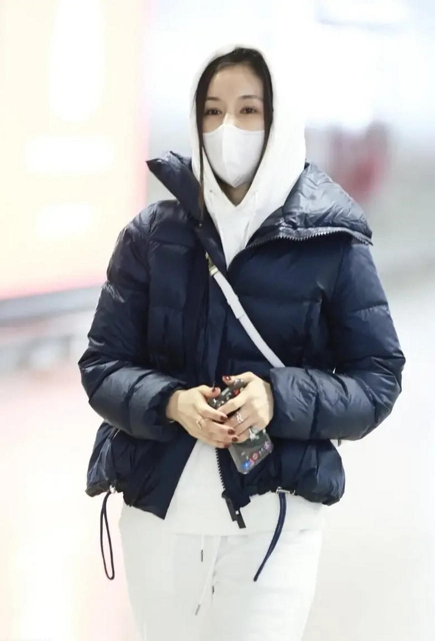 王子文穿一件藏蓝色的短款羽绒服,内搭白色连帽套装,裤子选用直筒版型