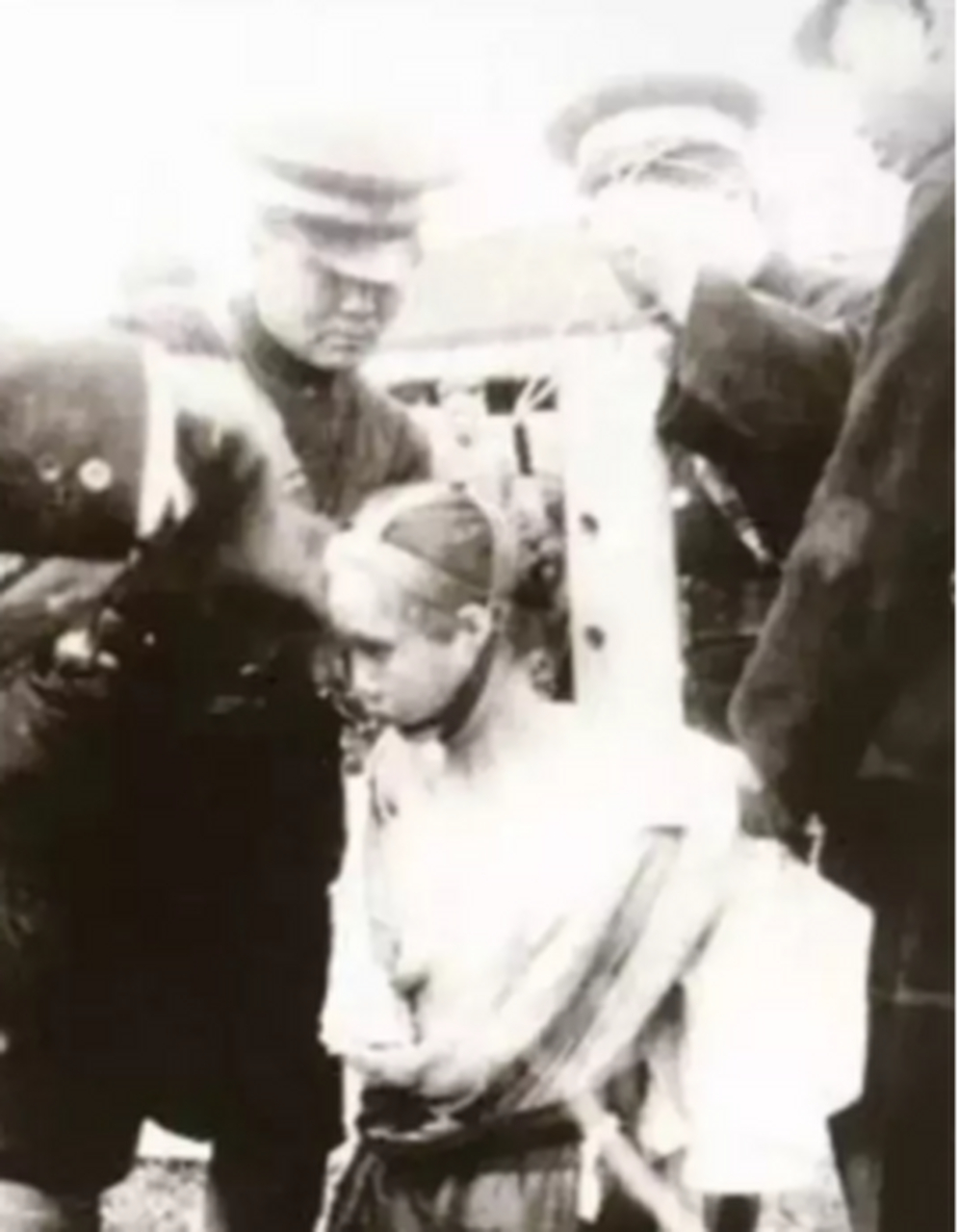 "处决的现场,镜头中赤身裸体跪着一名女子,旁边是几个正在行刑的警员