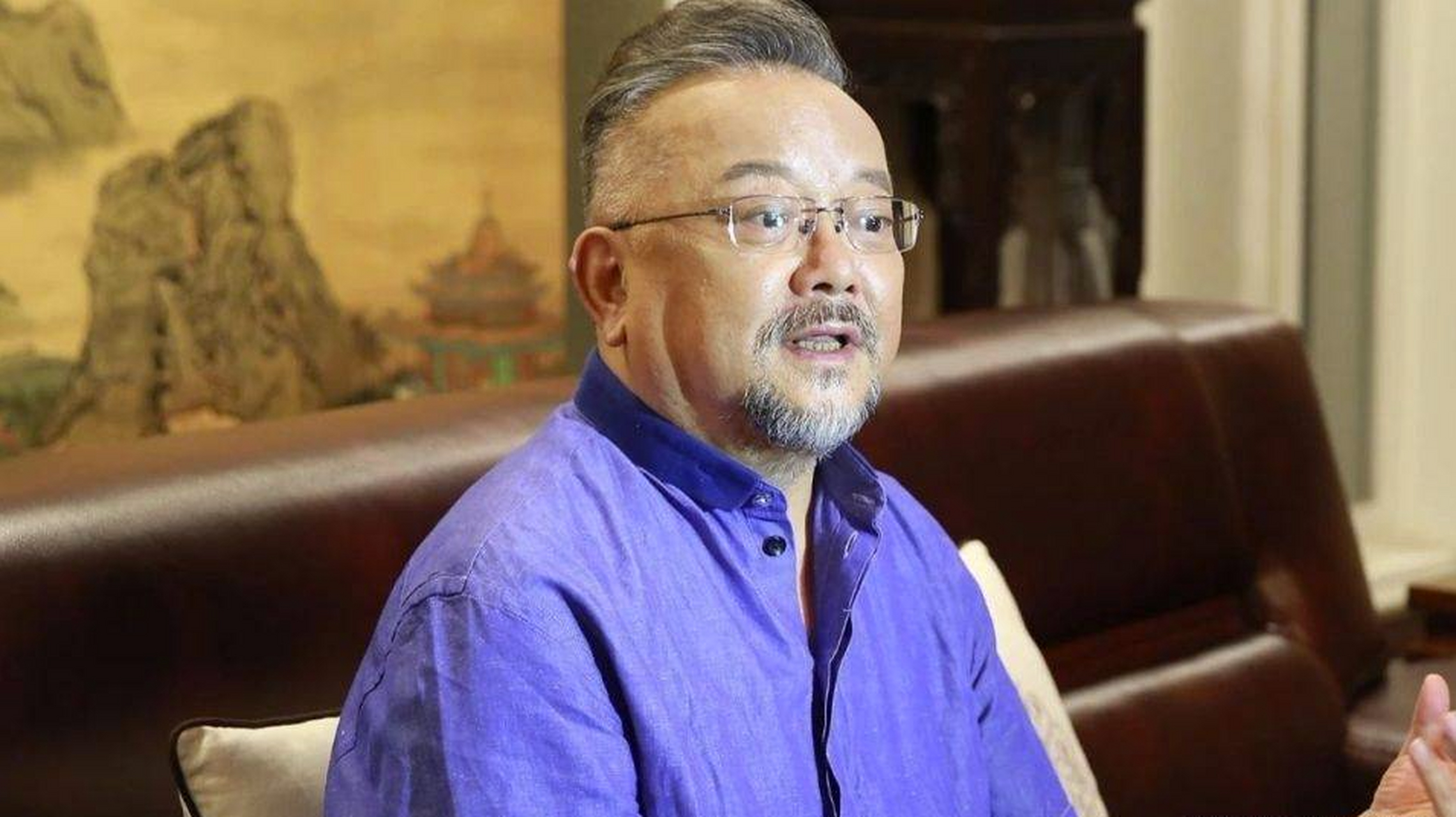 照片中的王刚戴着礼帽,身穿绿色t恤,在观众席上专注观看球赛.