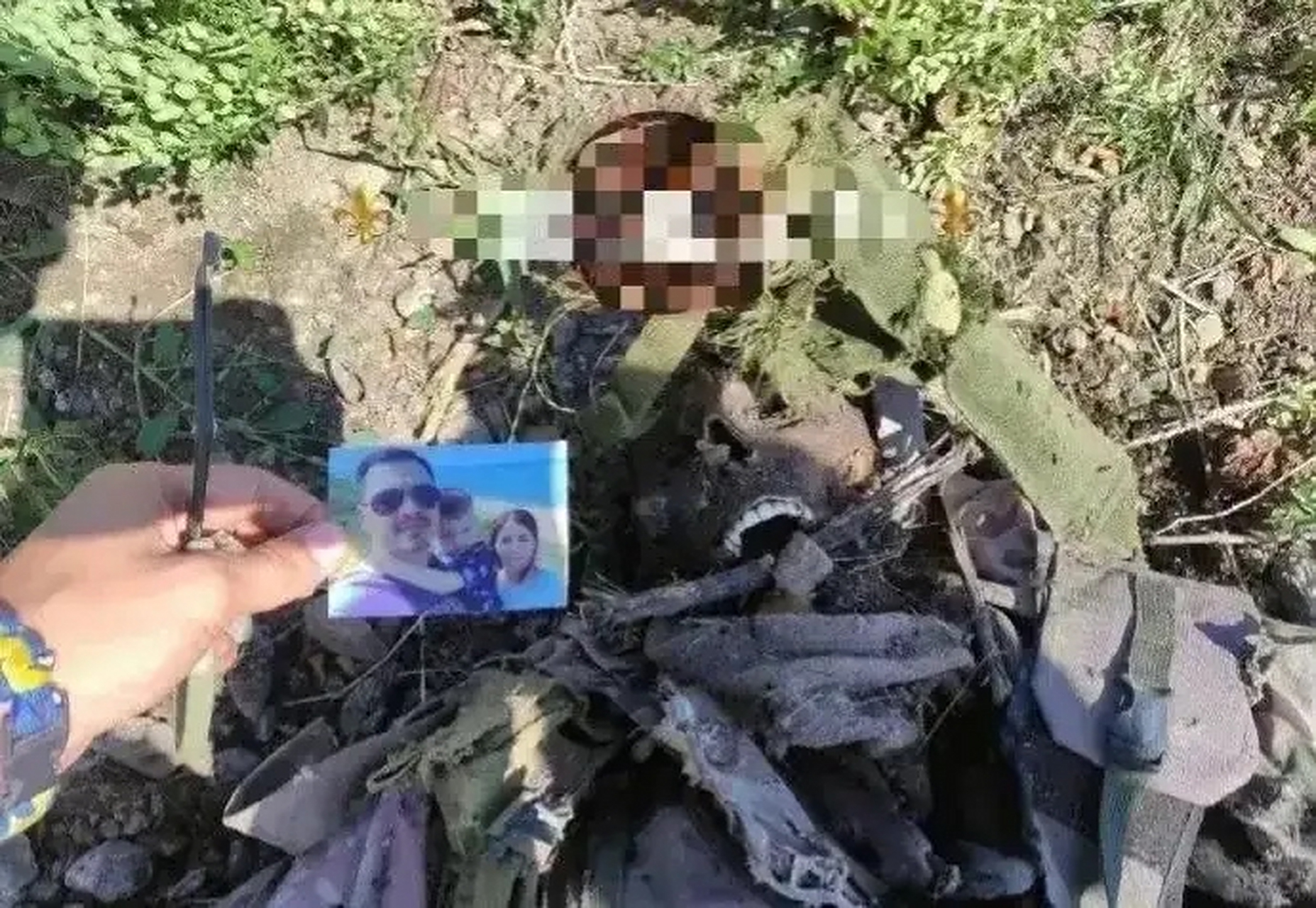俄乌战场,一名乌克兰士兵尸体已腐烂,只剩衣服及遗骨,还有一张全家福