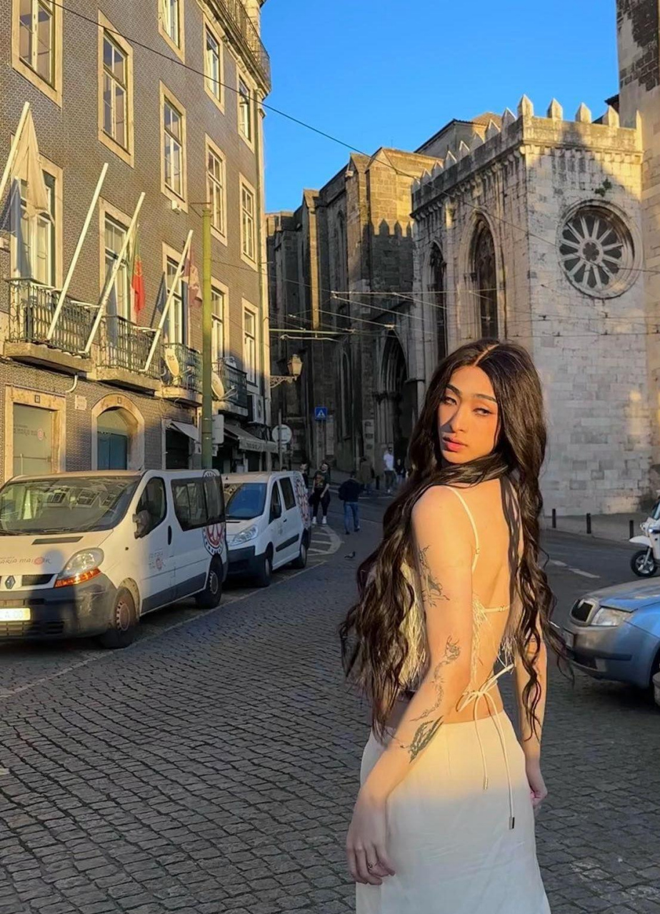 照片中的哈利穿着粉红色纱裙,化着精致的妆容,一头大波浪长发,戴着