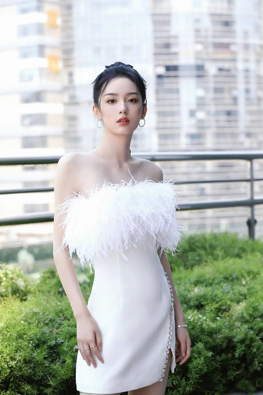 周也身着白色羽毛抹胸连衣裙展现出她优雅高贵的气息,轻盈的面料仿佛