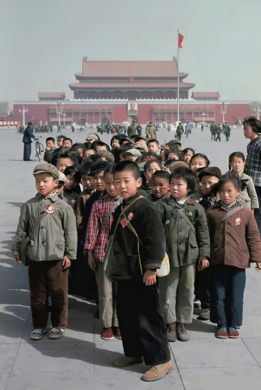 六十年代,一群穿着朴素的小学生在天安门广场前合影,从他们穿着打扮