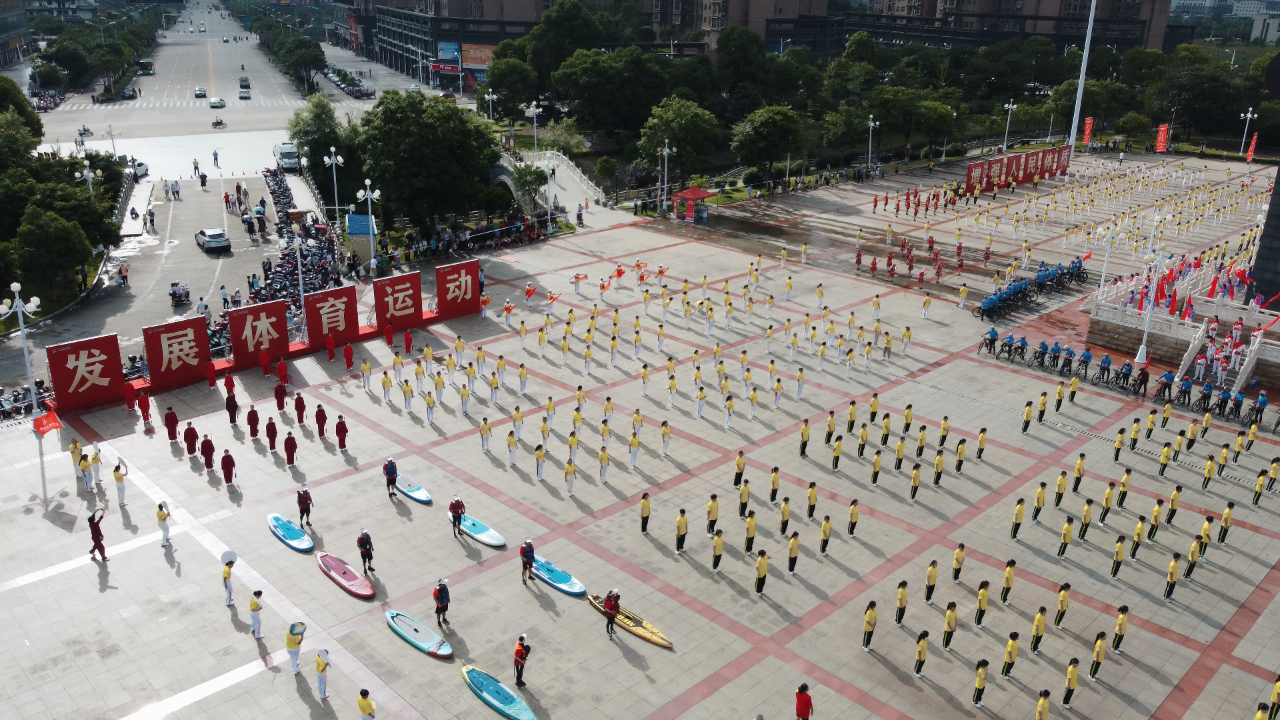 鸟瞰江华万人同跳广场舞活动现场,红黄服饰将广场装饰成彩色棋盘
