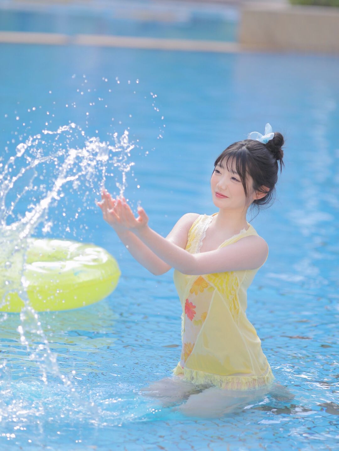 水中嬉戏玩耍的漂亮女孩,长相甜美可爱,淡黄色裙式泳装很漂亮