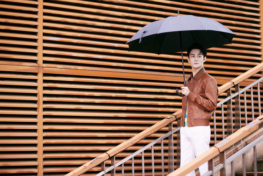 王凯穿复古皮衣化身儒雅君子 打伞扮酷尽显洒脱气质