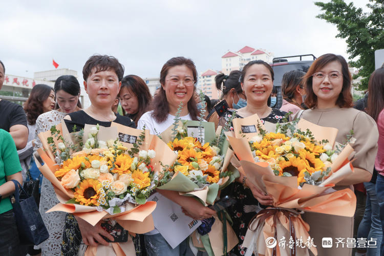 部分考生结束高考,考点前手捧鲜花和老师家长合影