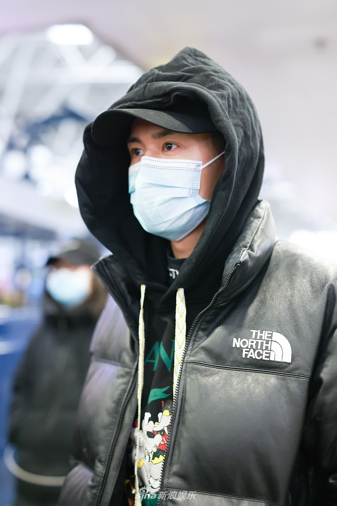 租入:张哲瀚穿涂鸦卫衣戴帽低调现身 双手插兜御寒模样可爱