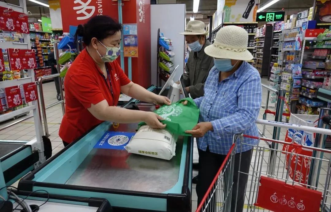 家乐福超市收银员为顾客发放环保购物袋,顾客对此次活动表示非常认可.