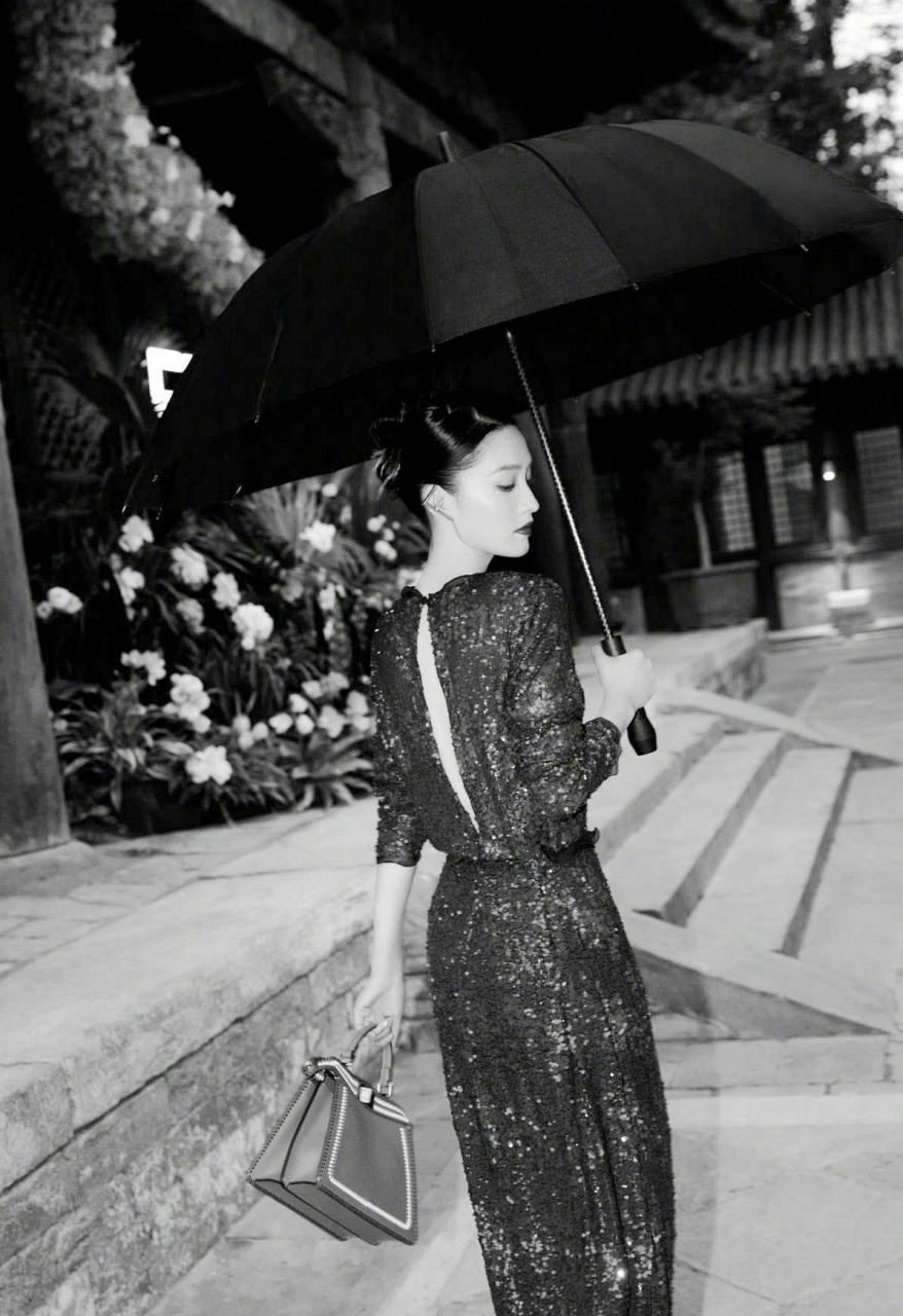 李沁打着一把大气感十足的雨伞,黑色亮片连衣裙完美的凸显了他的身材
