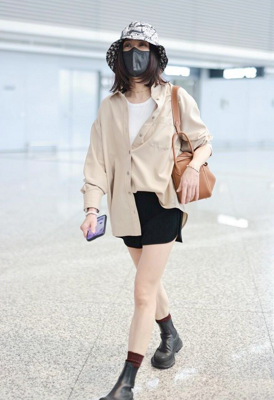 贾静雯机场街拍,卡其色衬衫配白衬衫,黑色短裤 短靴减龄!