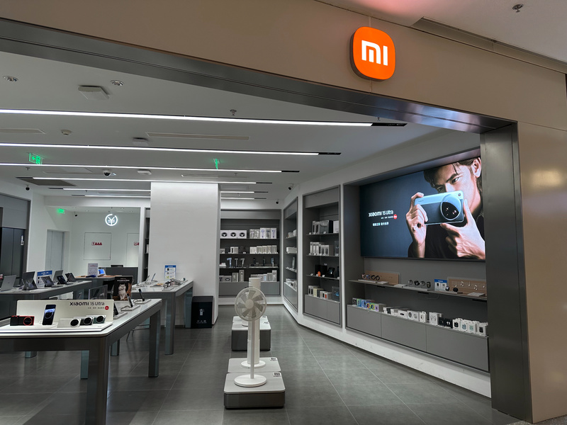 小米手机专卖店展示区，展示多款手机及配件，墙上有广告海报。