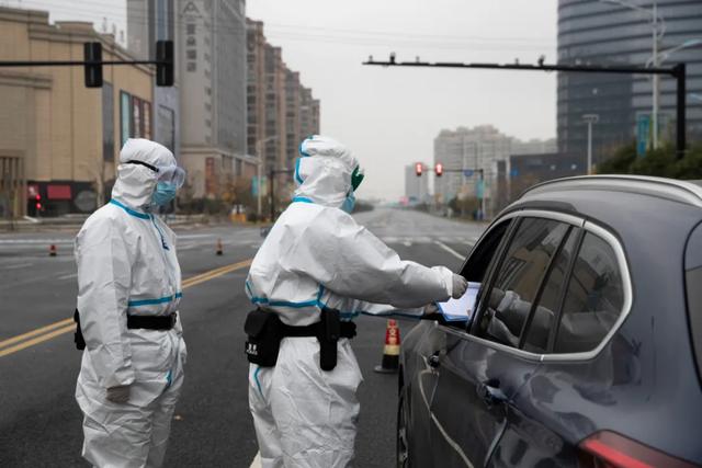 12月12日,疫情防控人员在浙江省绍兴市上虞区复兴路上对过往车辆和
