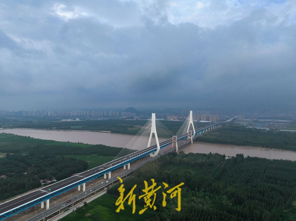 在济南黄河大桥附近,天空翻滚的云团与奔腾的黄河水相互映照,展现了