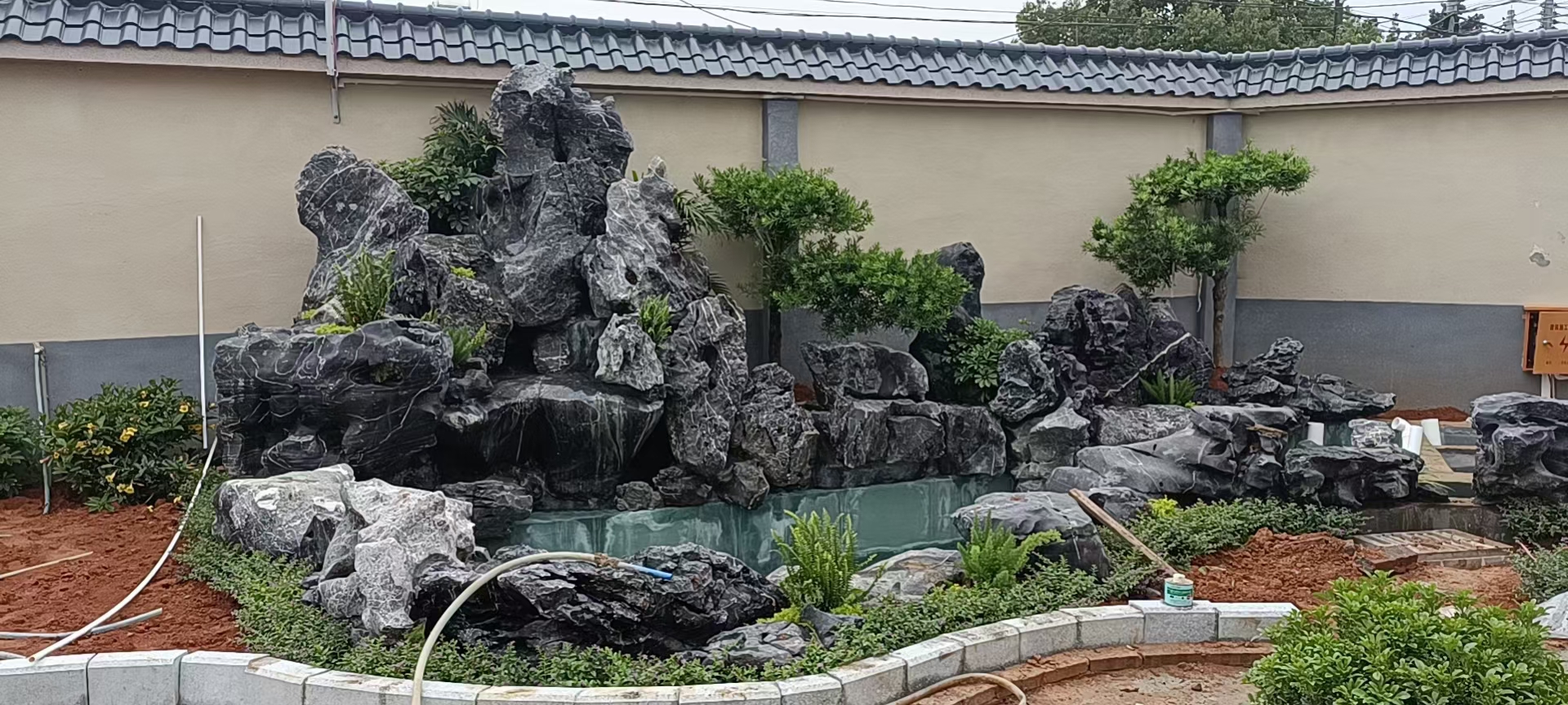 湖北黑山石批发,湖北黑山石在庭院造景,庭院黑山石假山制作图片