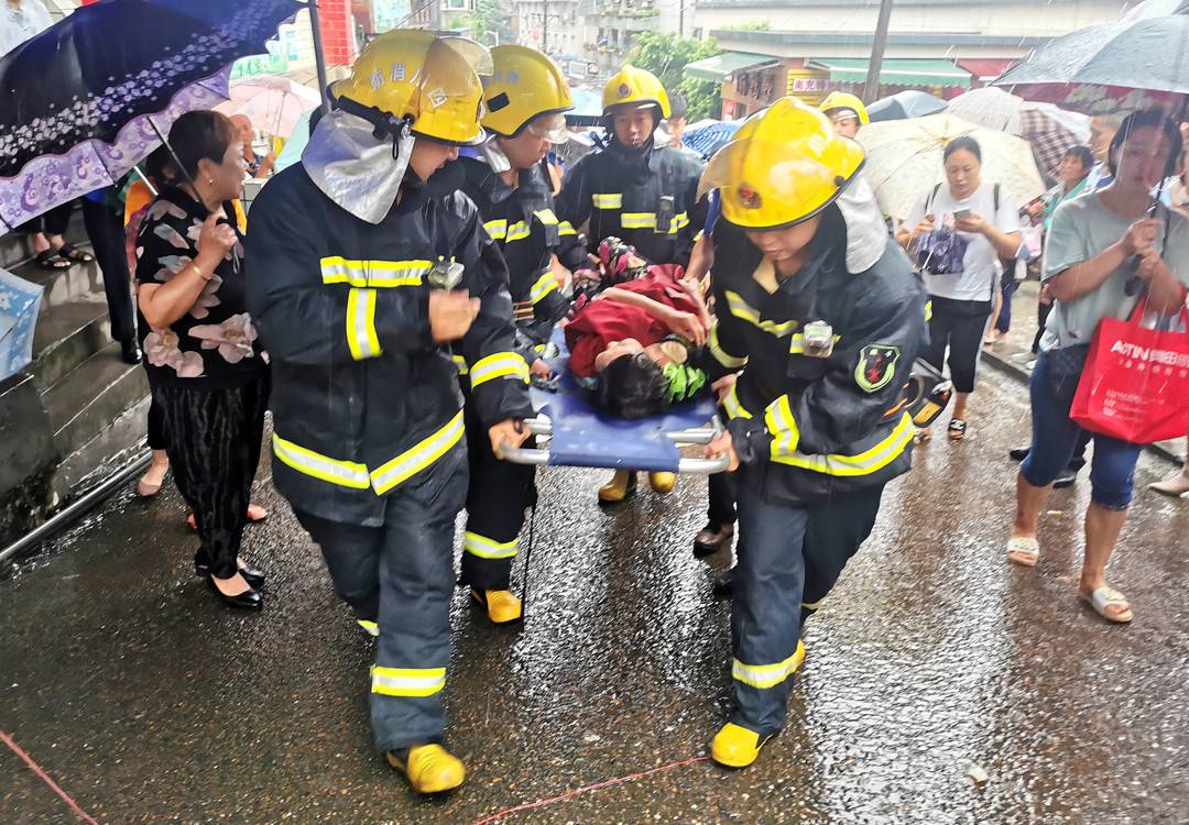 消防隊員雨中救援受傷老人,群眾撐傘為老人遮雨