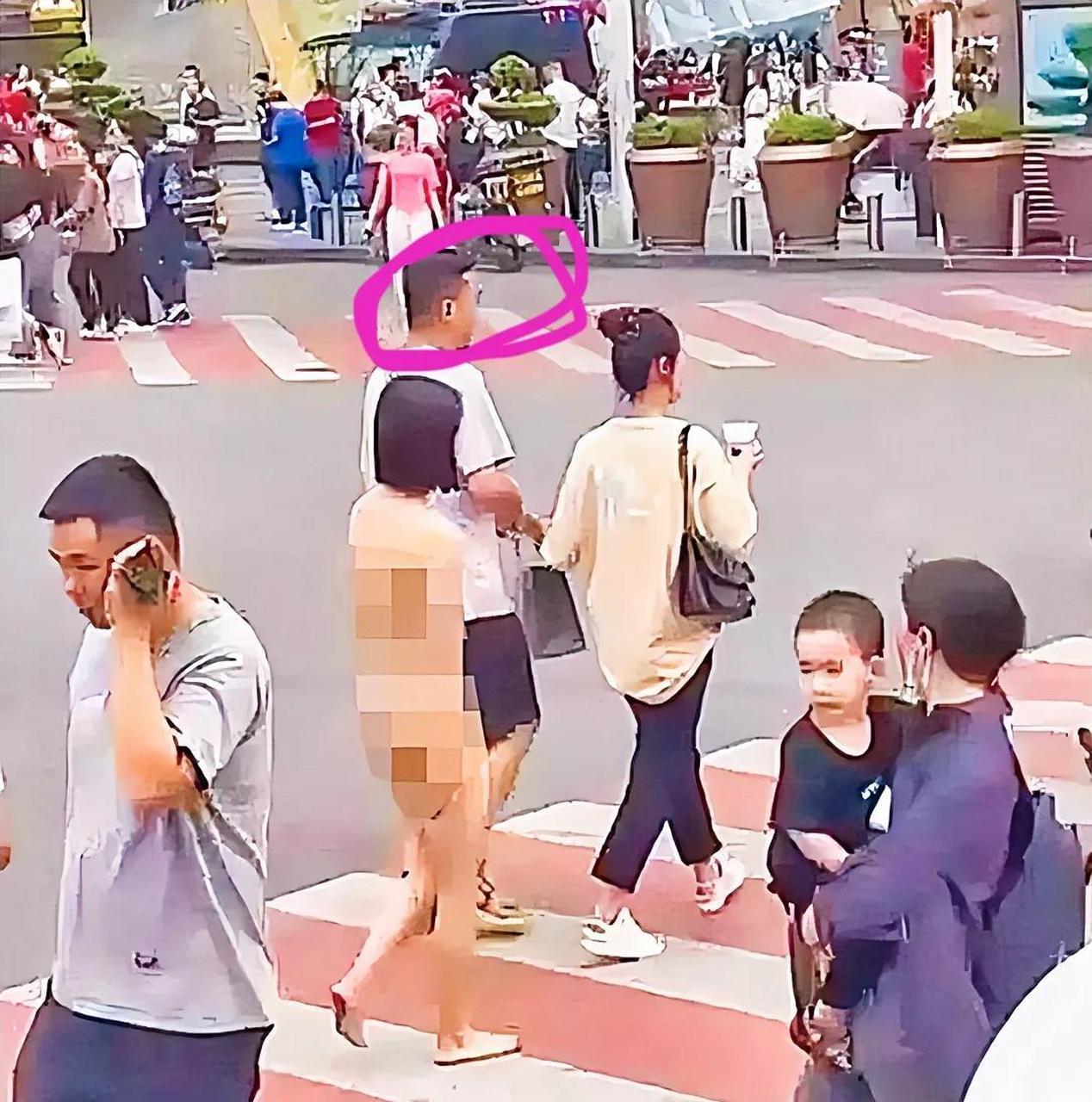 一位长相靓丽,身材错落有致的年轻女子光着身子从一家服装店里走了