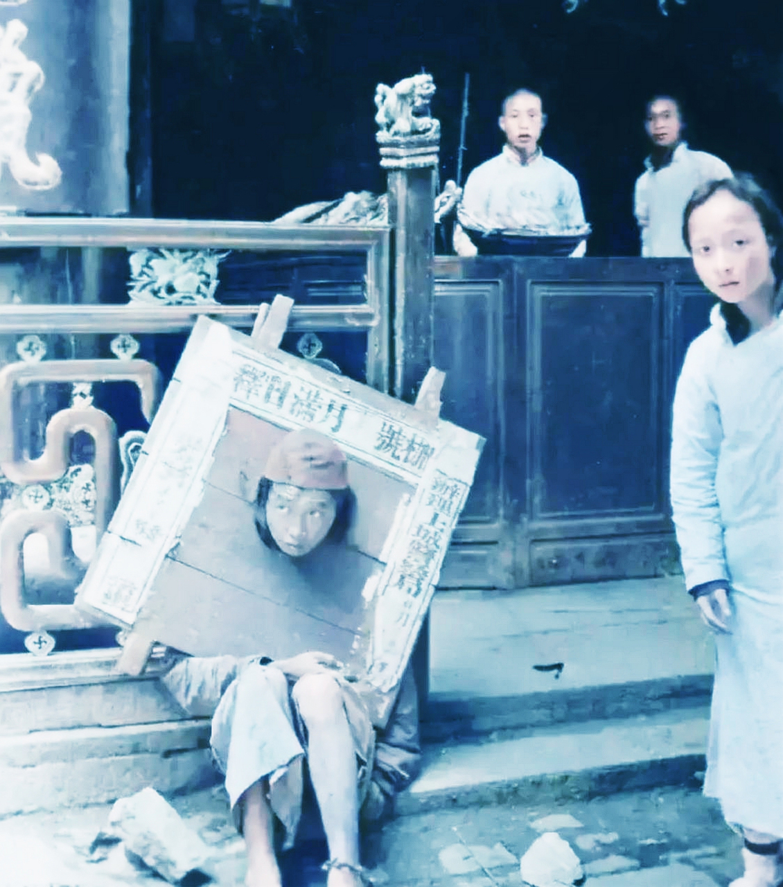 他头戴圆顶礼帽,赤脚,身着粗布衣裳,脖子上套着重达十多斤的木制脚镣