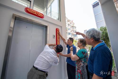 居民们为新加装的电梯贴上对联,喜迎开通.