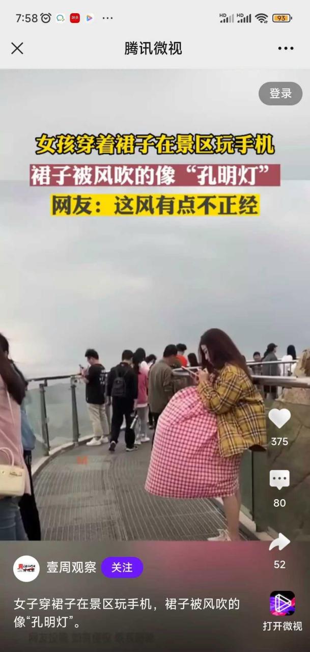 女子在风景区玩手机,裙子里面灌满了风. 这是风不正经,还是风在助人.