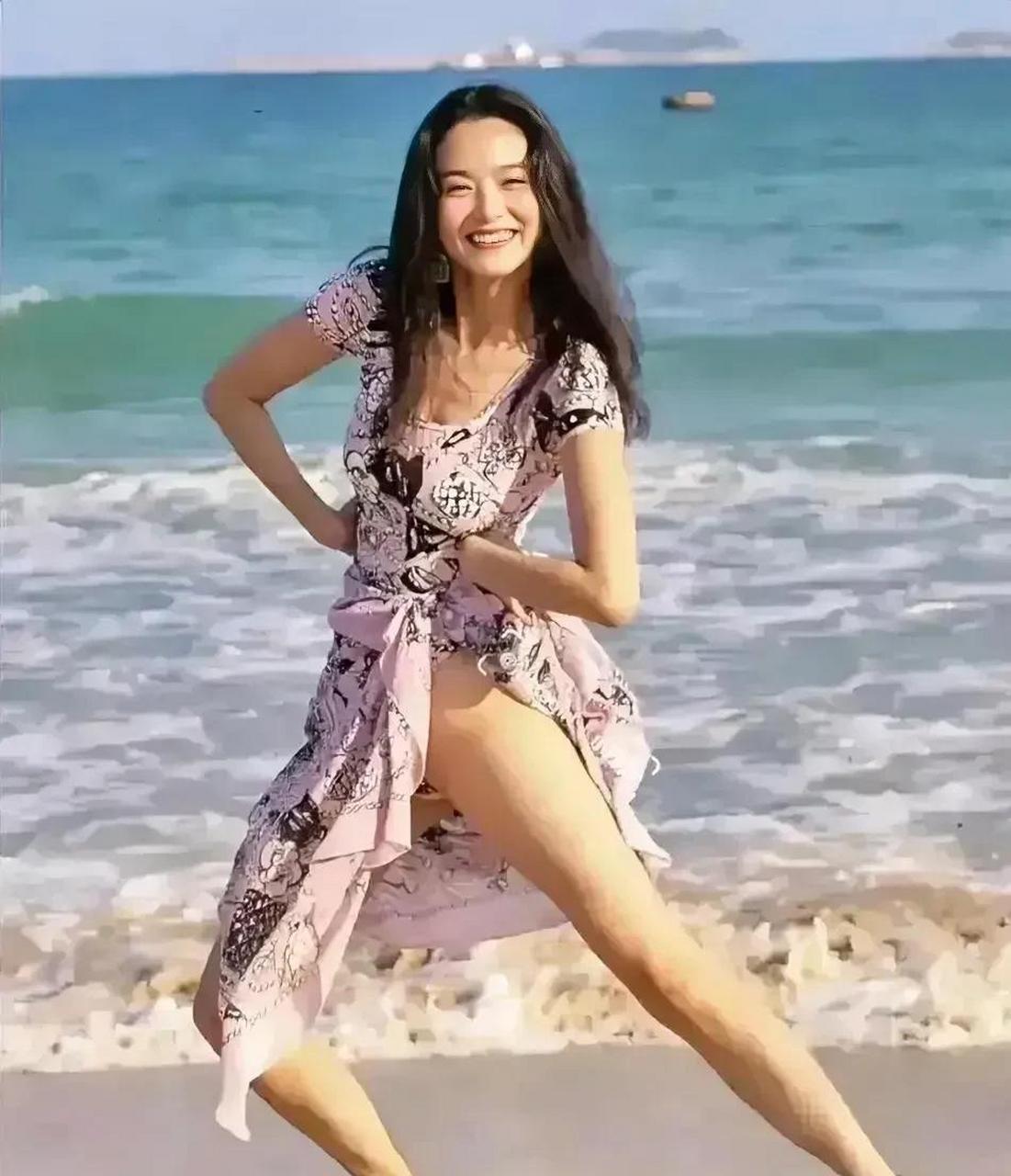 在林青霞年轻时的海滩照片中,她身穿一件迷人的碎花连衣裙,双手优雅地