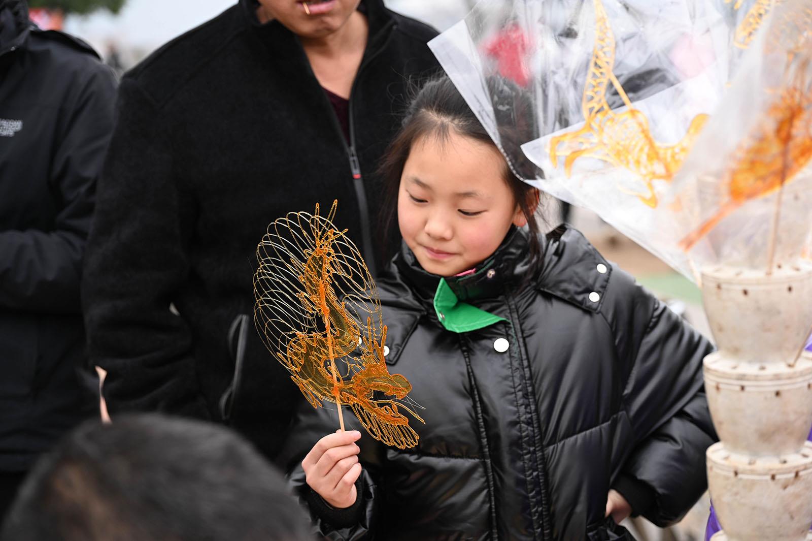 1月14日,蓝山县塔下寺文化广场一角,糖画艺人魏树华正在熟练制作糖 