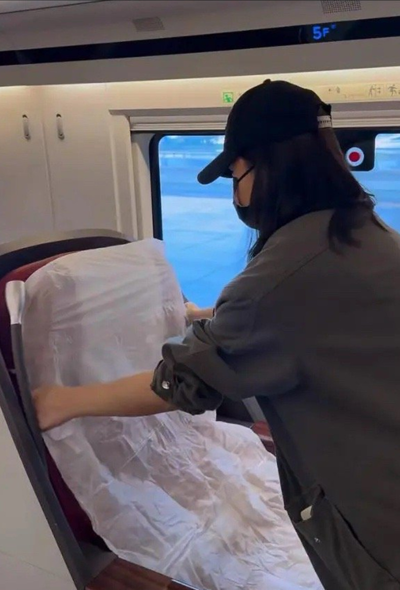 乘客在火车上帮忙整理座位上的枕头和被褥