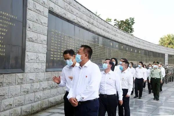 市委书记刘向东神情庄重地来到花篮前,整理缎带.