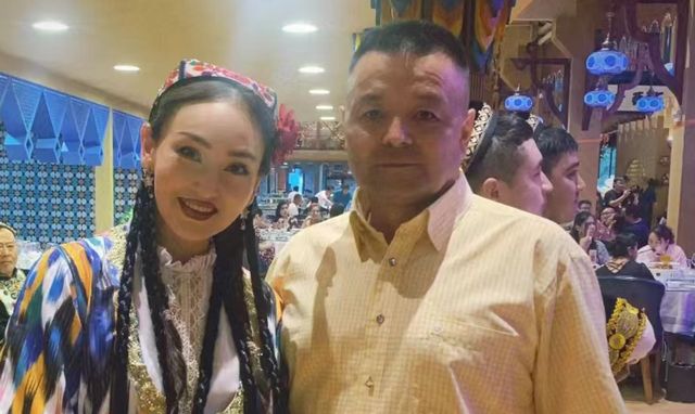 迪丽热巴爸爸参加活动,和美女亲切合影,身材高大方圆脸不像热巴