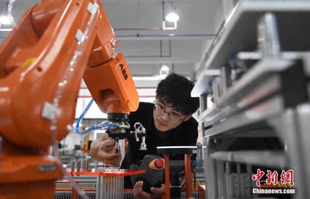 资料图：一家机器人生产企业的工作人员在调试机器人设备。 中新社记者 王刚 摄